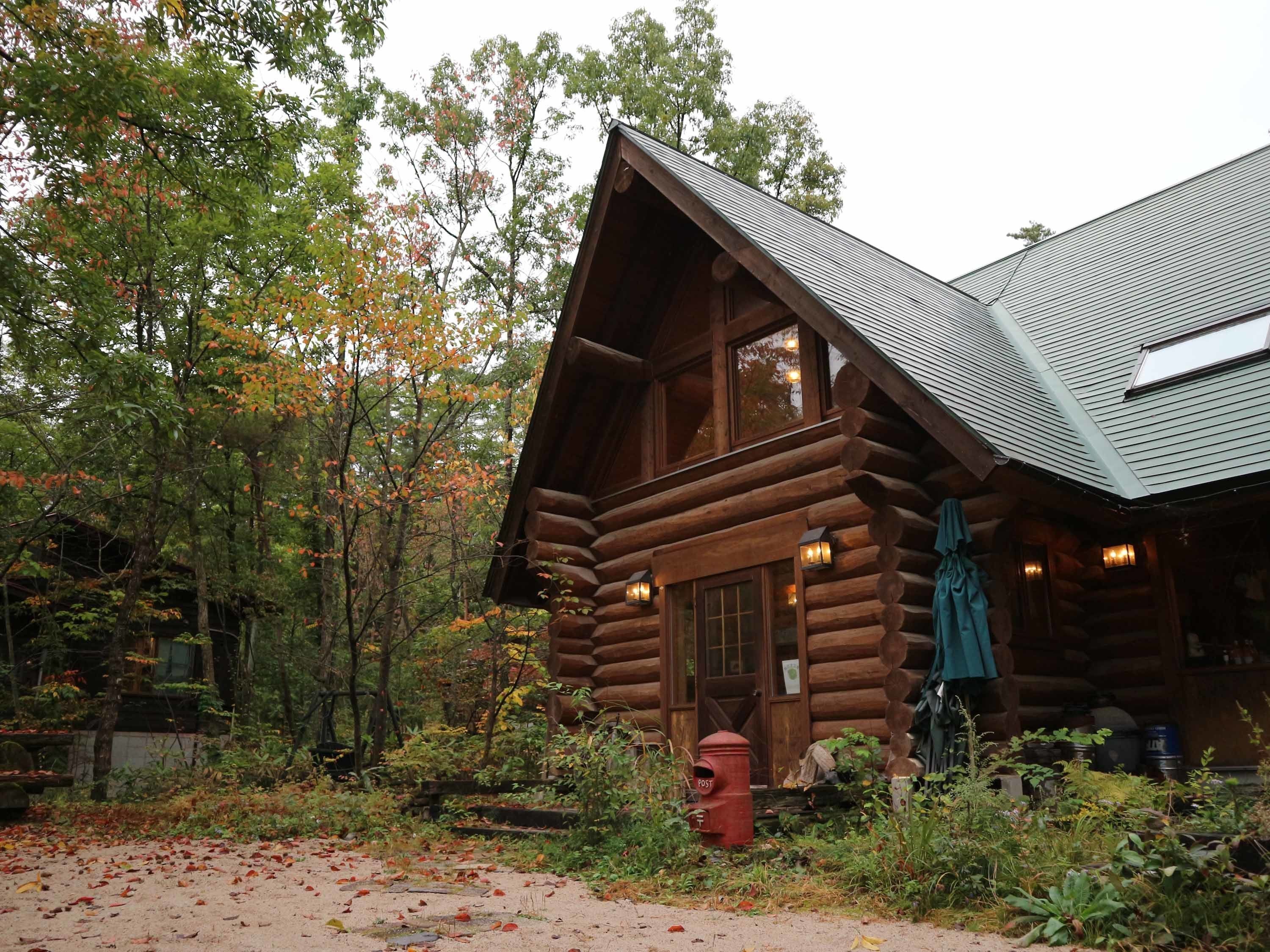 A log cabin with a steeply pitched roof, large windows, and a fire hydrant in front.