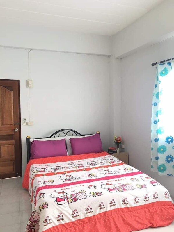 Un dormitorio con una cama, una mesita de noche, una ventana con cortina y una puerta.