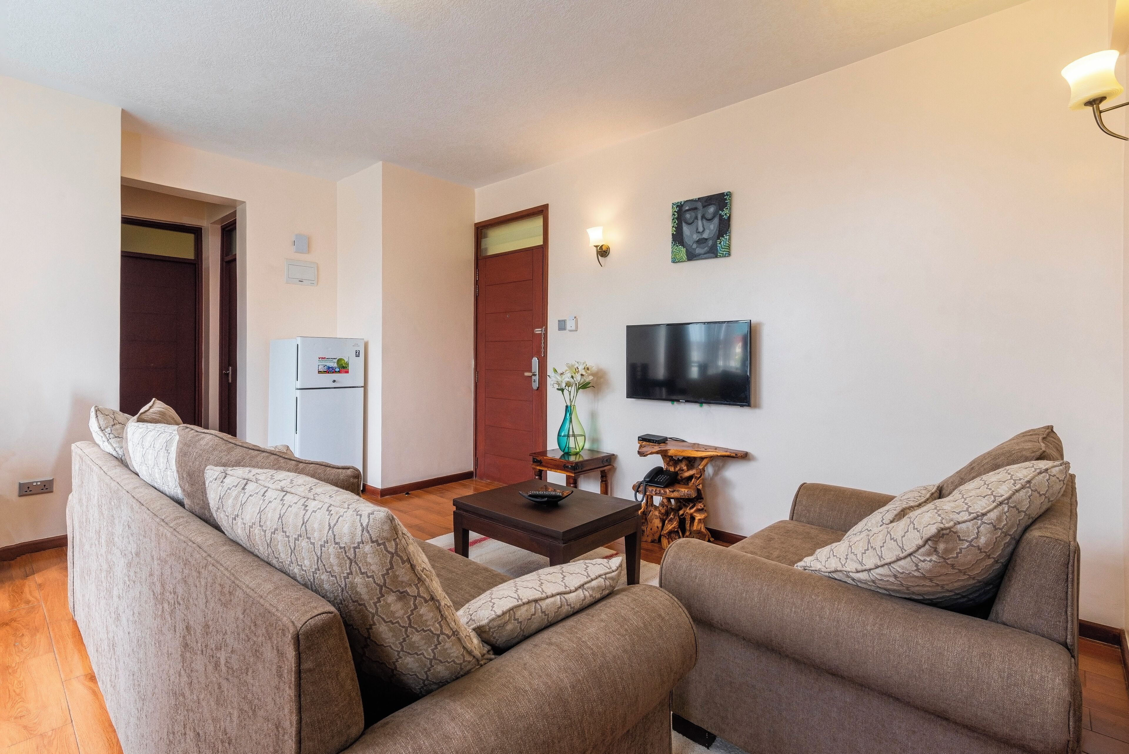 A living room with two sofas, a coffee table, a TV, and a refrigerator.