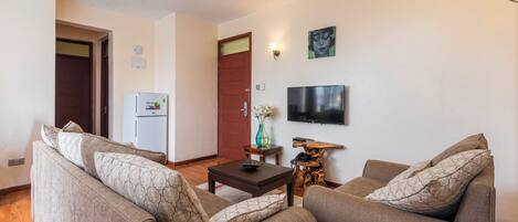 A living room with two sofas, a coffee table, a TV, and a refrigerator.