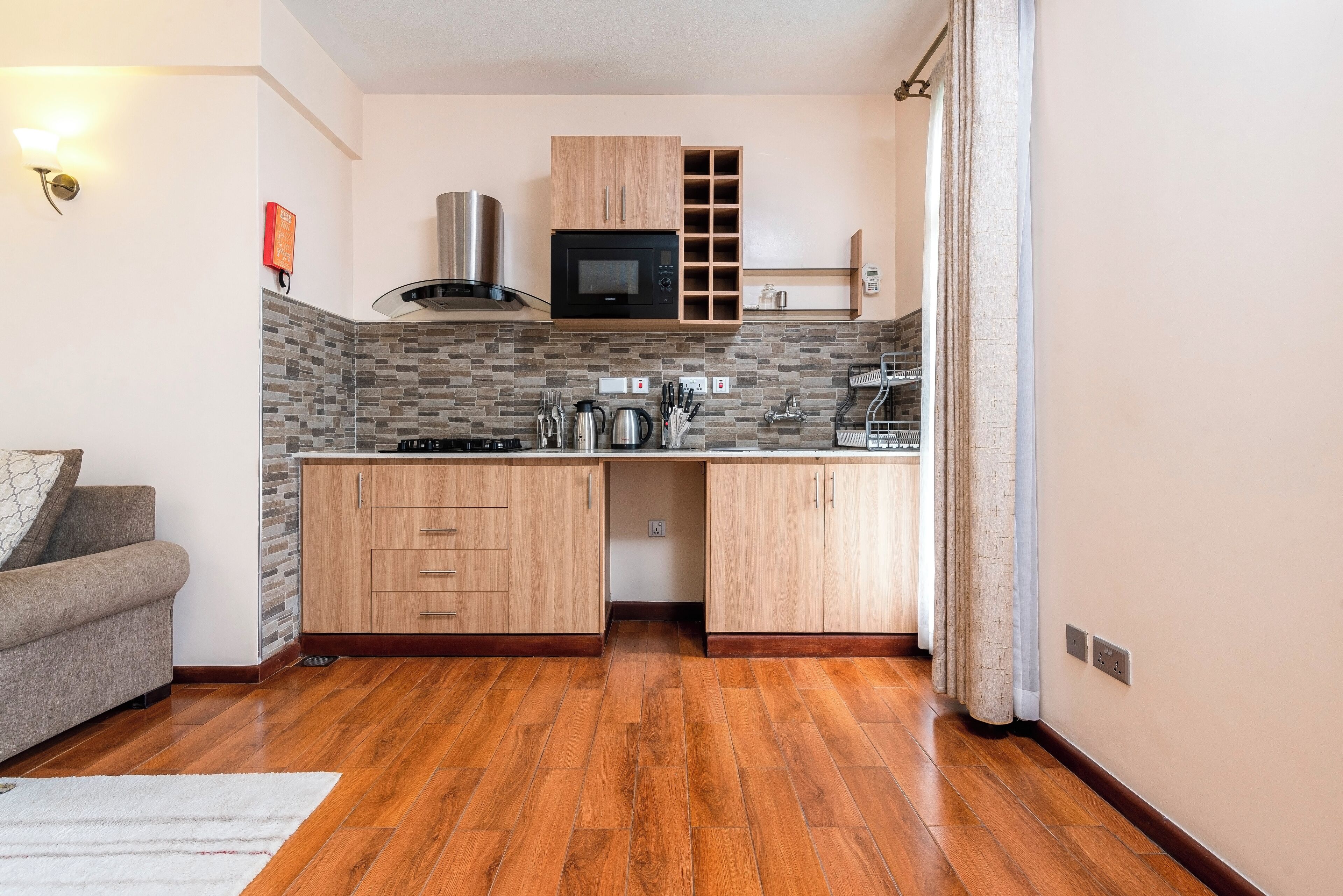 A compact kitchen with wooden cabinets, a microwave, and a gas stove.