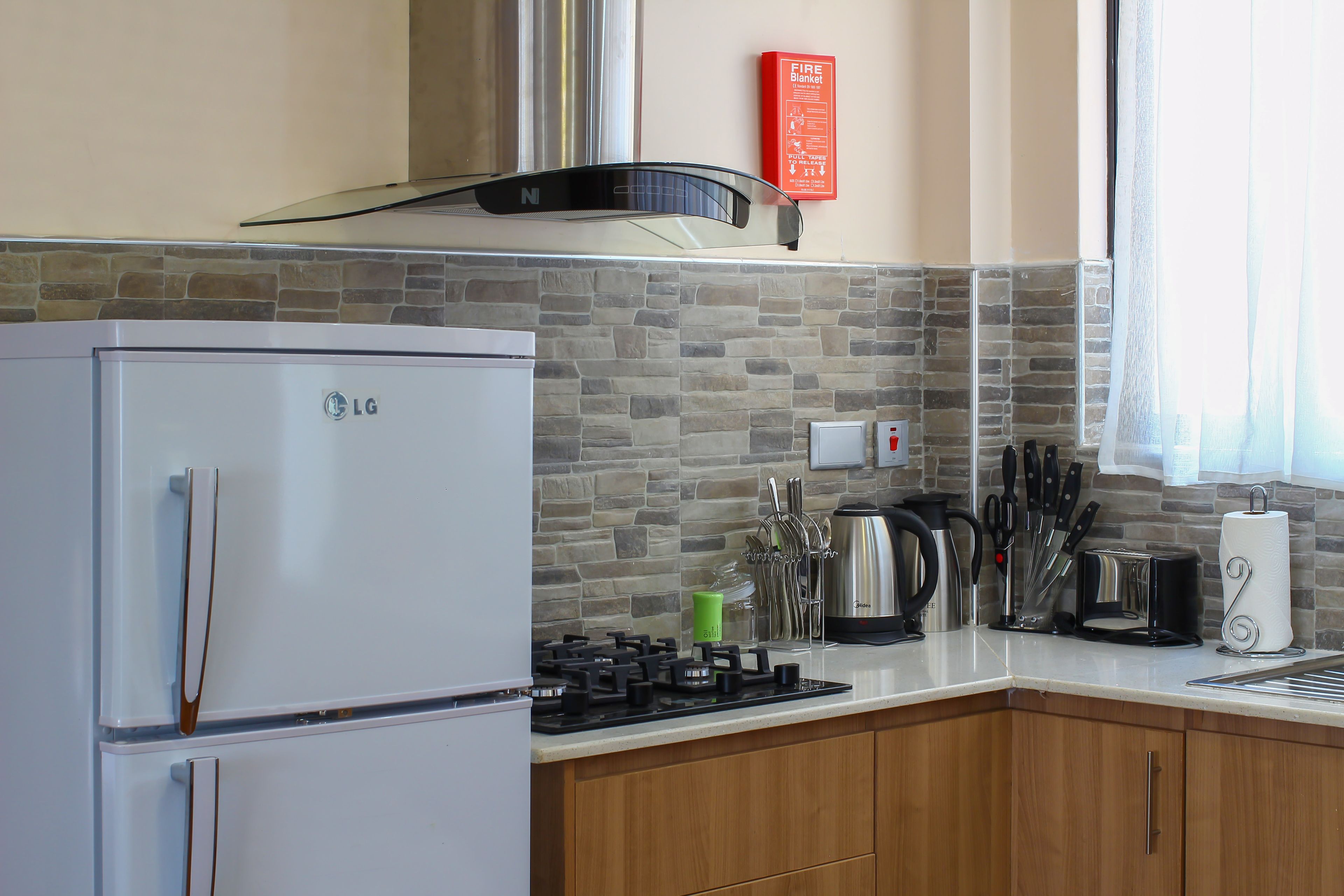 Una cocina con refrigerador, estufa y diferentes utensilios.