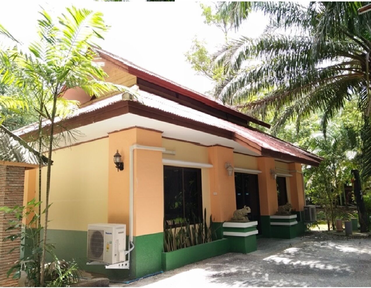 A two-story building with a red roof, green and orange walls, and a covered entrance area.