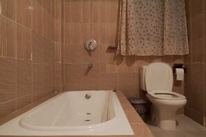 A bathroom with a bathtub, toilet, and shower curtain.