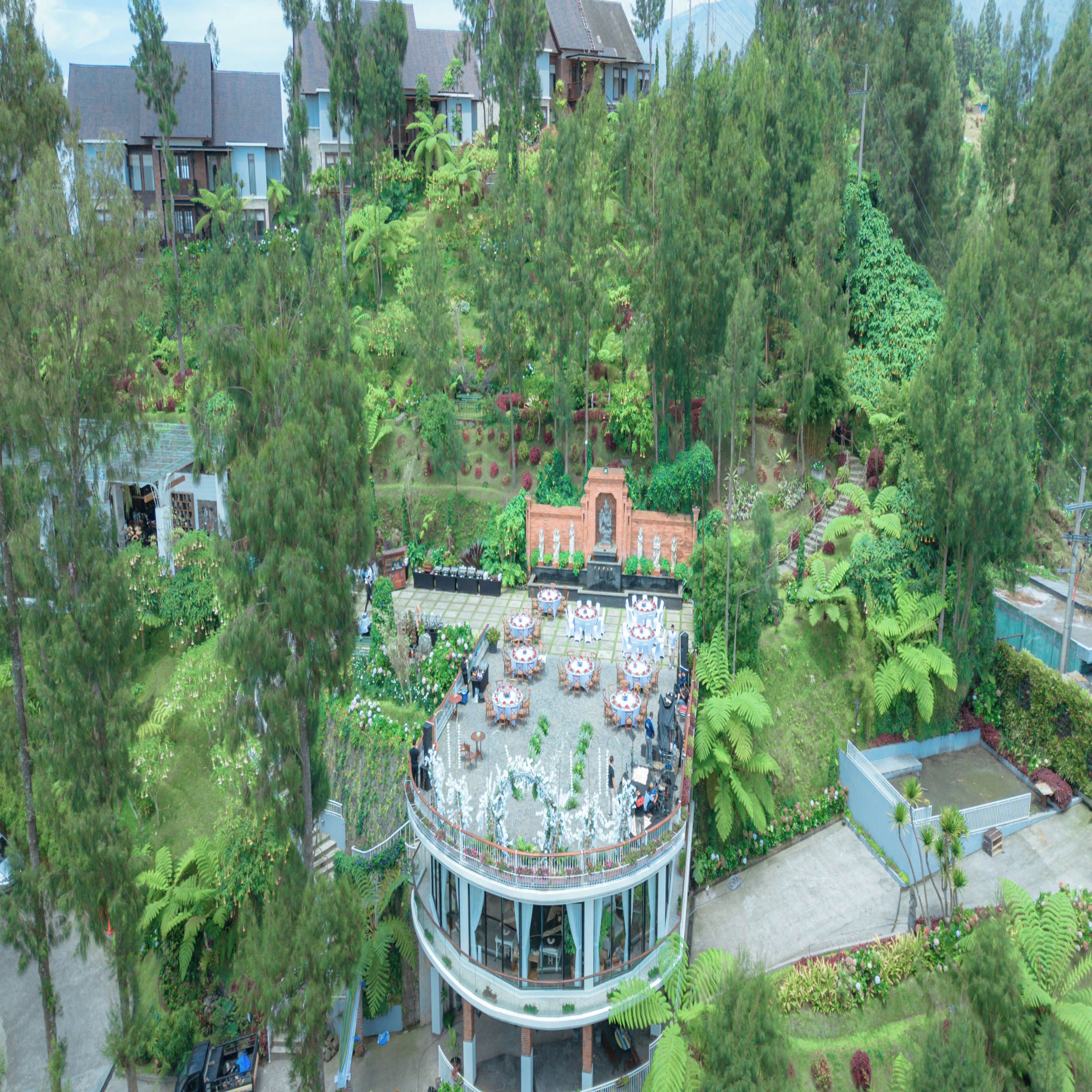 A hotel with a circular building surrounded by lush greenery and a patio area with outdoor seating.