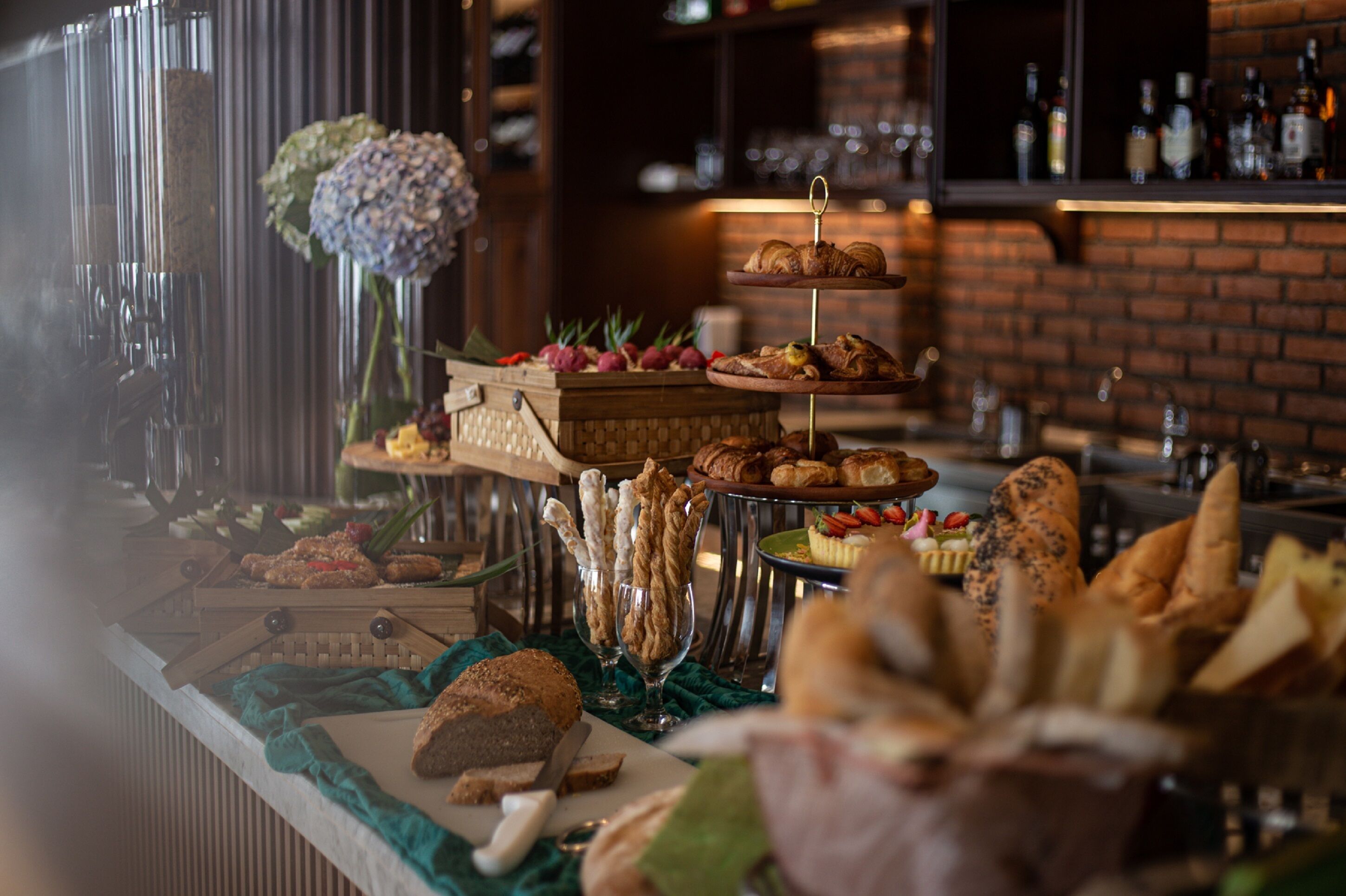 A buffet with various food items and a brick wall in the background.