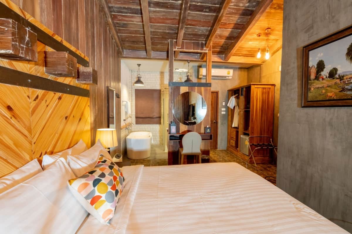 A bedroom with a bed, a desk, a chair, a mirror, and a wardrobe.