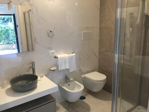 Un baño moderno con lavamanos, bidé e inodoro de mármol.
