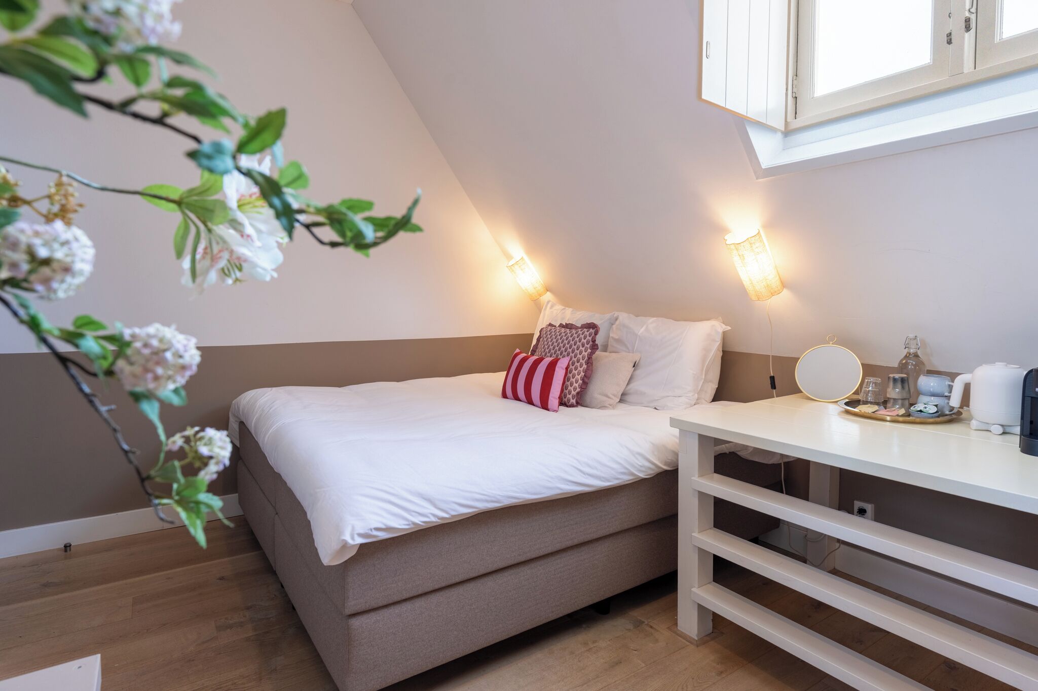 A bedroom with a bed, bedside table, and a window.