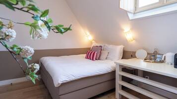 A bedroom with a bed, bedside table, and a window.