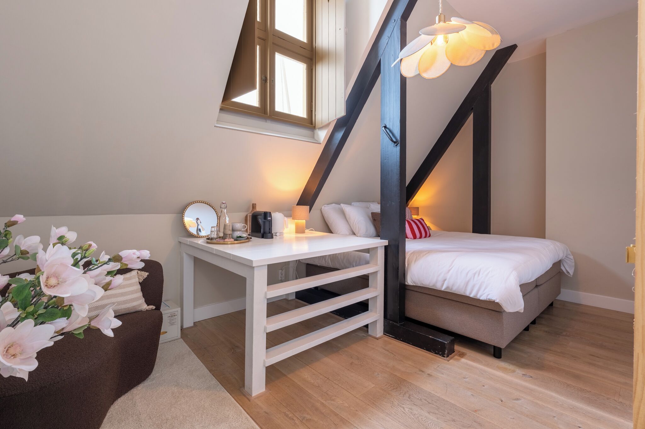 A bedroom with a bed, a desk, a chair, a window, and a ceiling light.