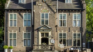 Een historisch hotel met een opvallende toren, grote ramen en een statig entree.