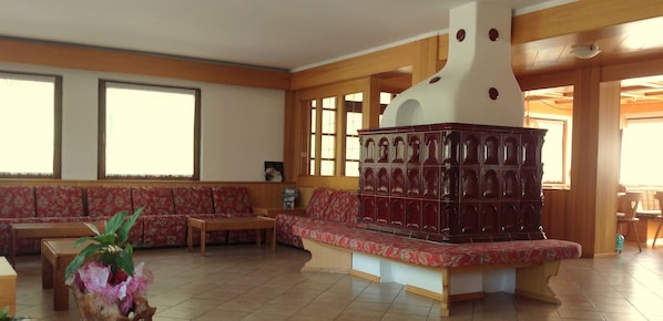 A living room with a wooden bench, a sofa, and a decorative fireplace. - Hotel Belvedere (Panchia)