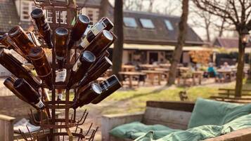 A metal sculpture of beer bottles arranged in a tree-like structure outdoors.
