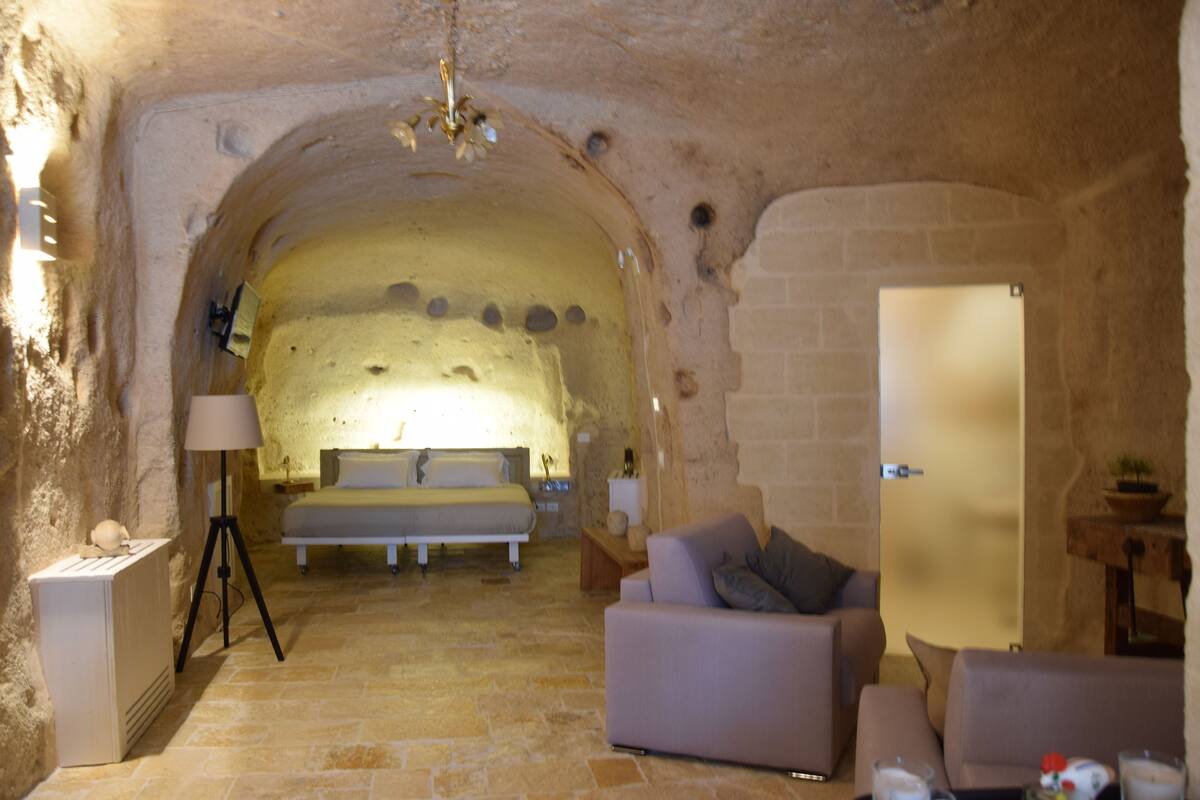 Una stanza accogliente con un letto, un divano e una lampada.