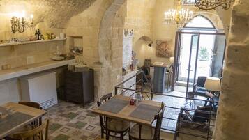 A rustic stone interior with a dining area, kitchen, and a view of the outside.