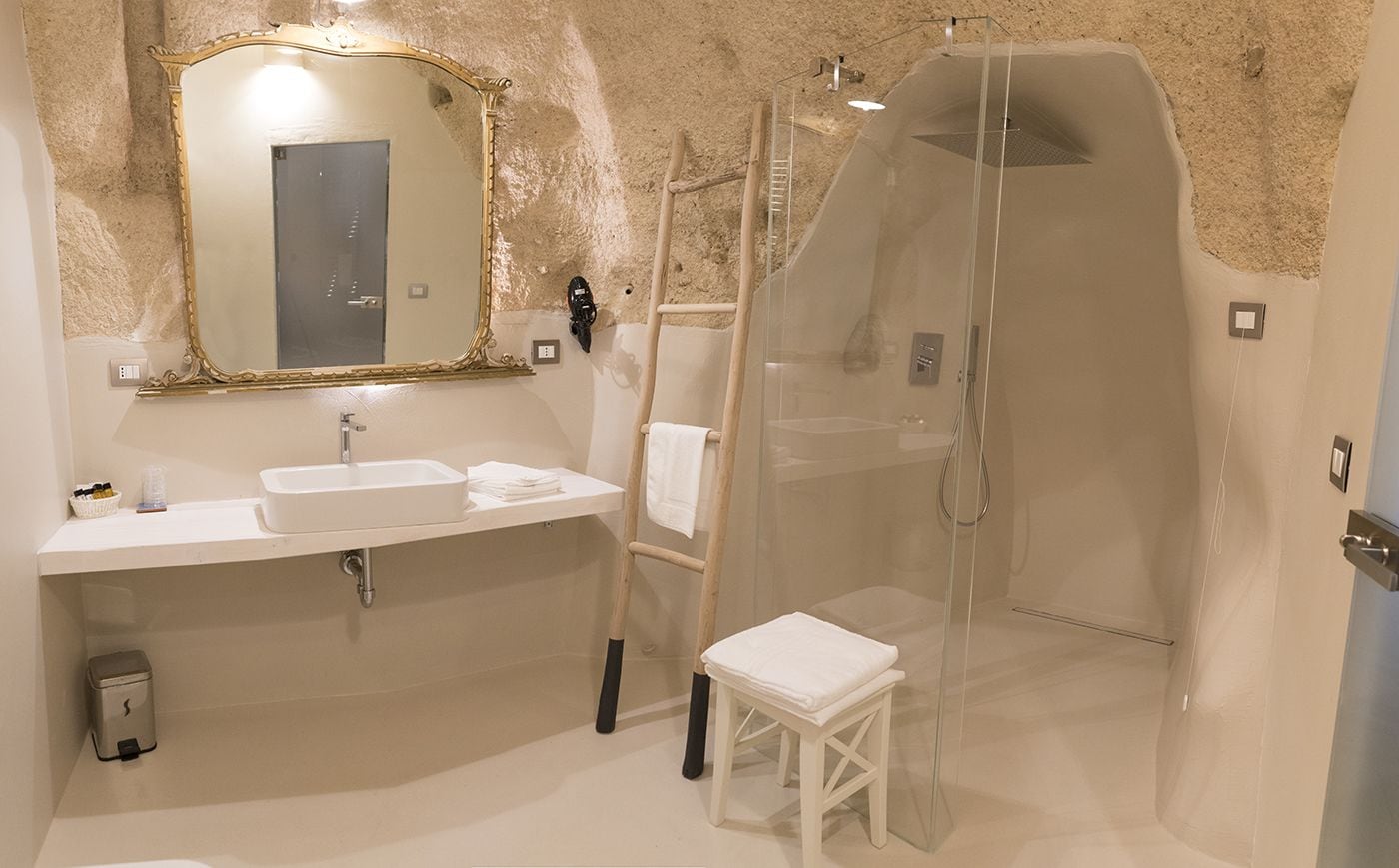 A bathroom with a sink, mirror, and shower enclosure.