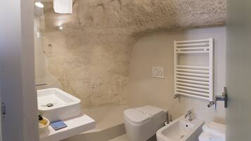 A bathroom with a sink, toilet, bidet, and towel rack.