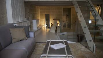 A modern living room with a sofa, a glass table, and a staircase.