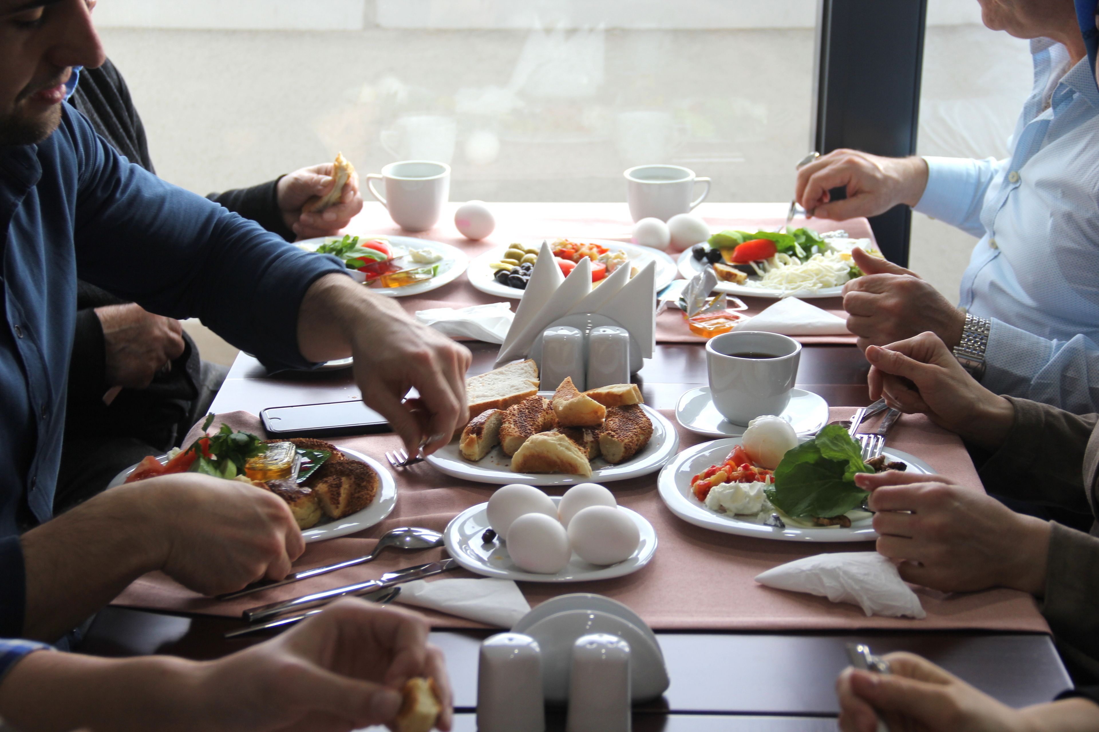 A group of people dining at a table with various dishes, including eggs, bread, and vegetables.