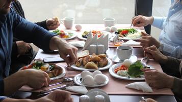 A group of people dining at a table with various dishes, including eggs, bread, and vegetables.