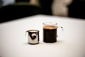 A small metal container and a glass mug with a handle on a white surface. - Novelty Hotel (Istanbul)