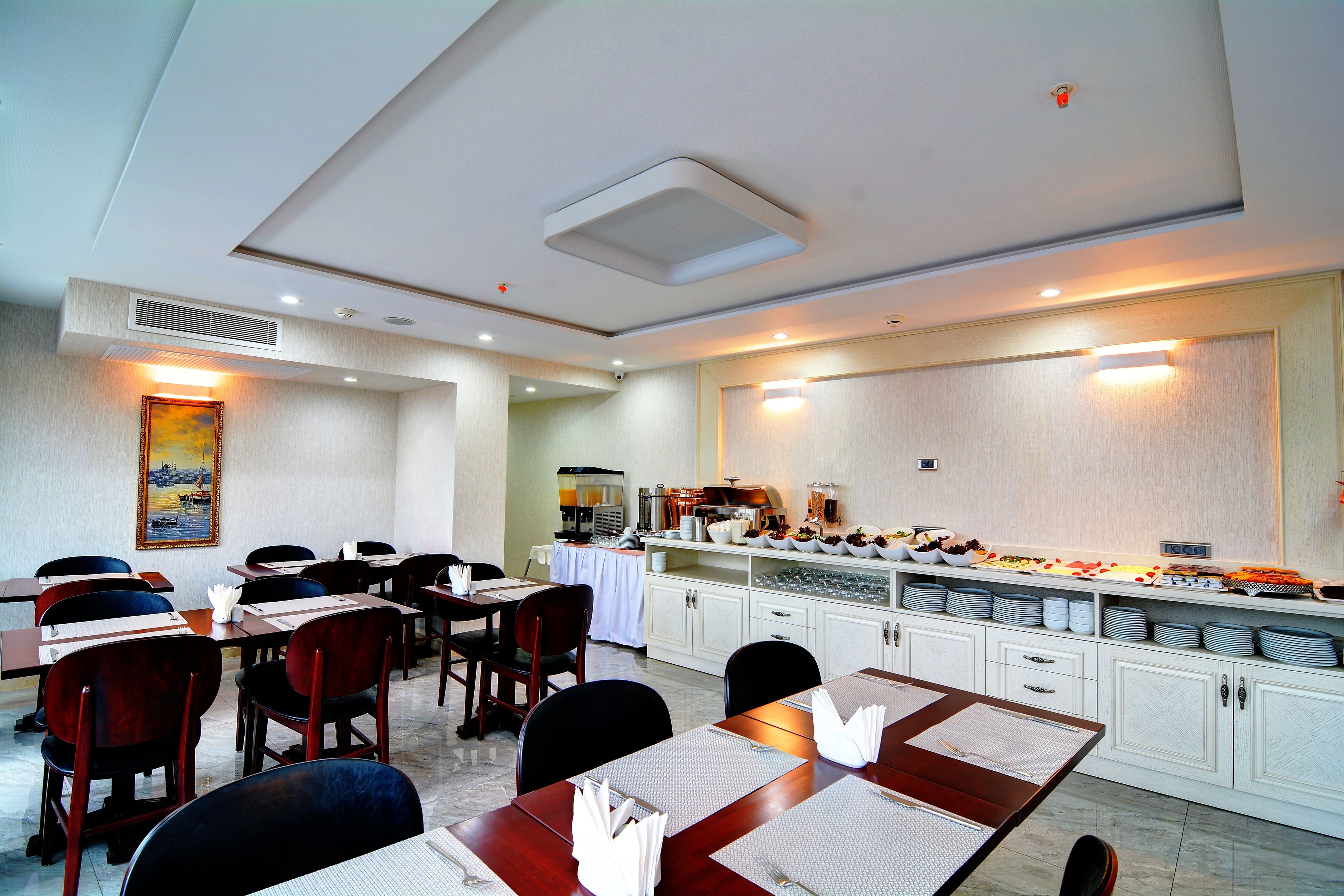A conference room with tables and chairs, a buffet area with food and drinks, and a kitchen in the background.