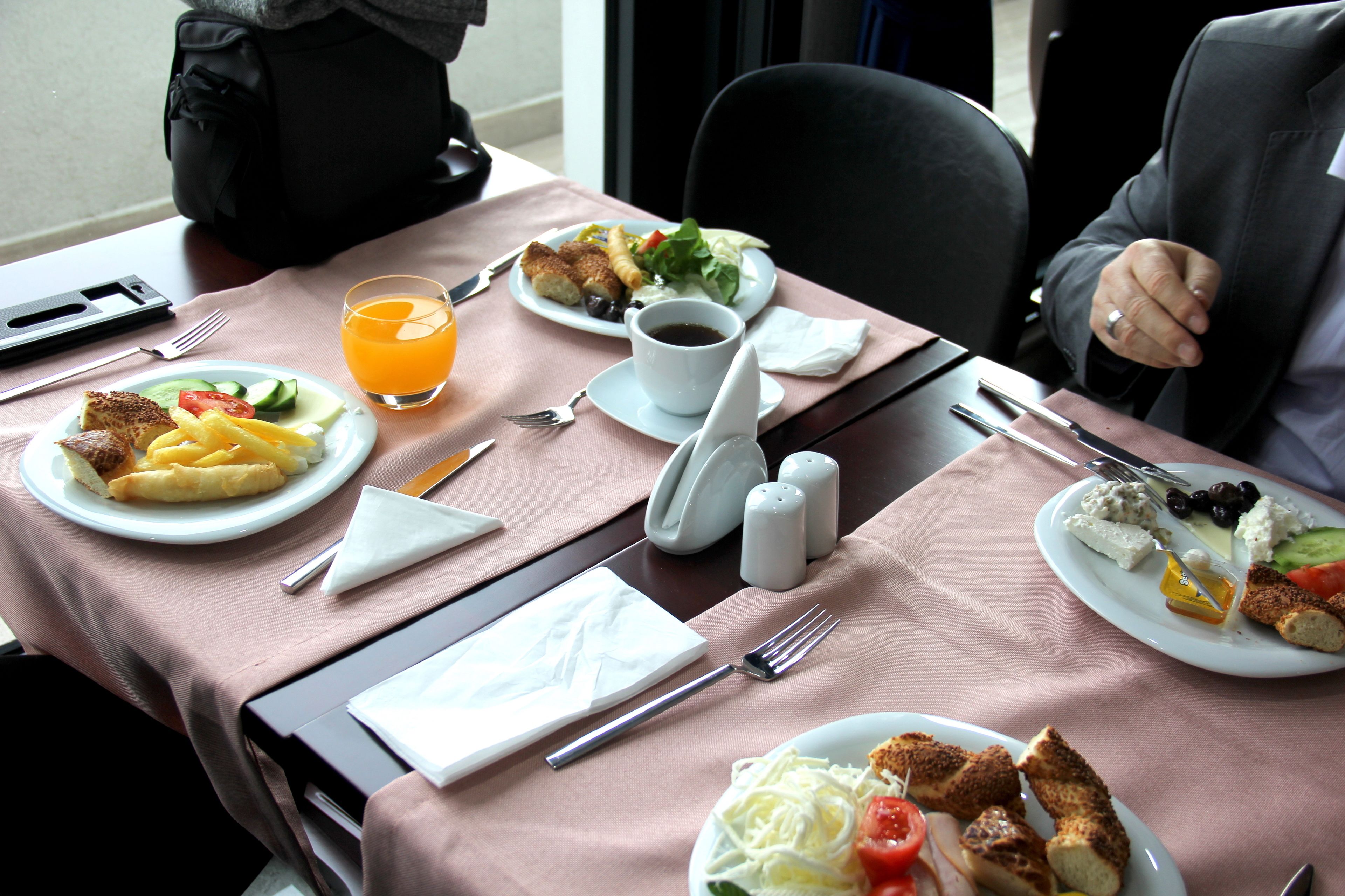 Una mesa servida con platos de comida, un vaso de jugo de naranja y cubiertos.