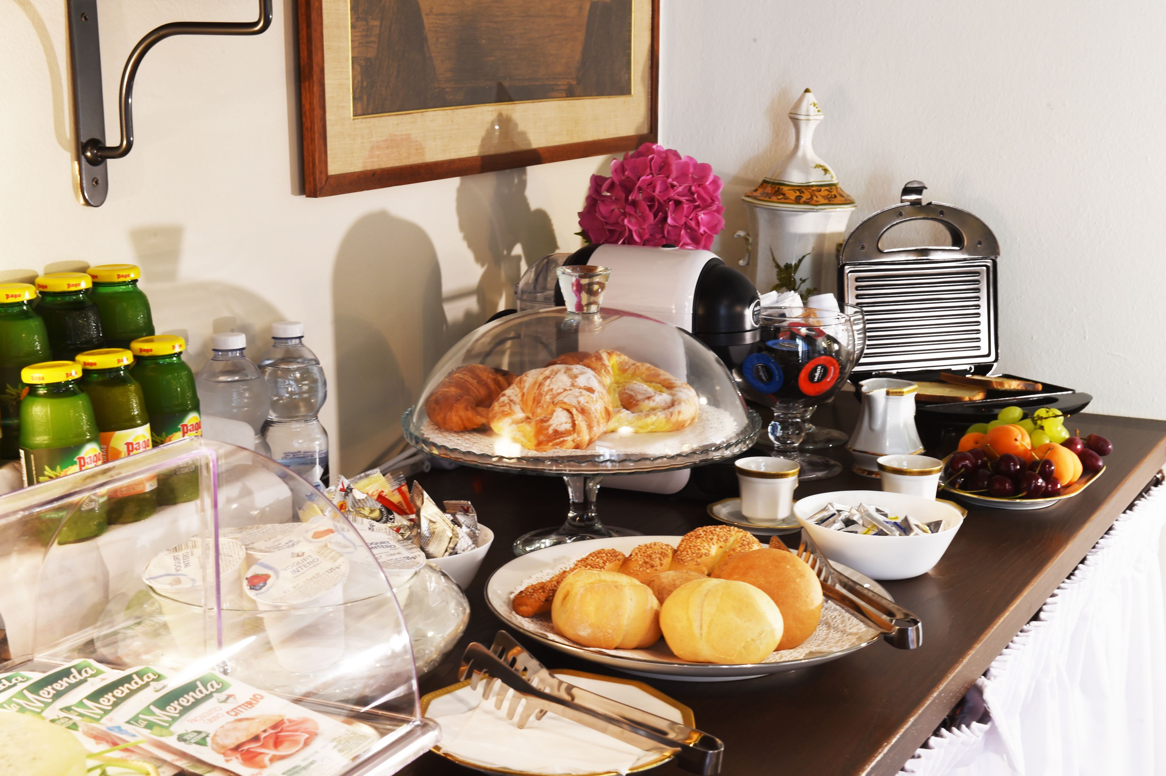 A buffet table with various food items, including pastries, fruits, and condiments.