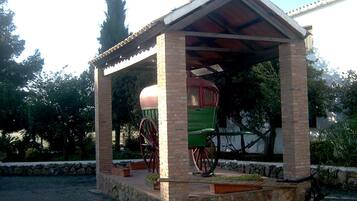 A brick pavilion with a green carriage inside.