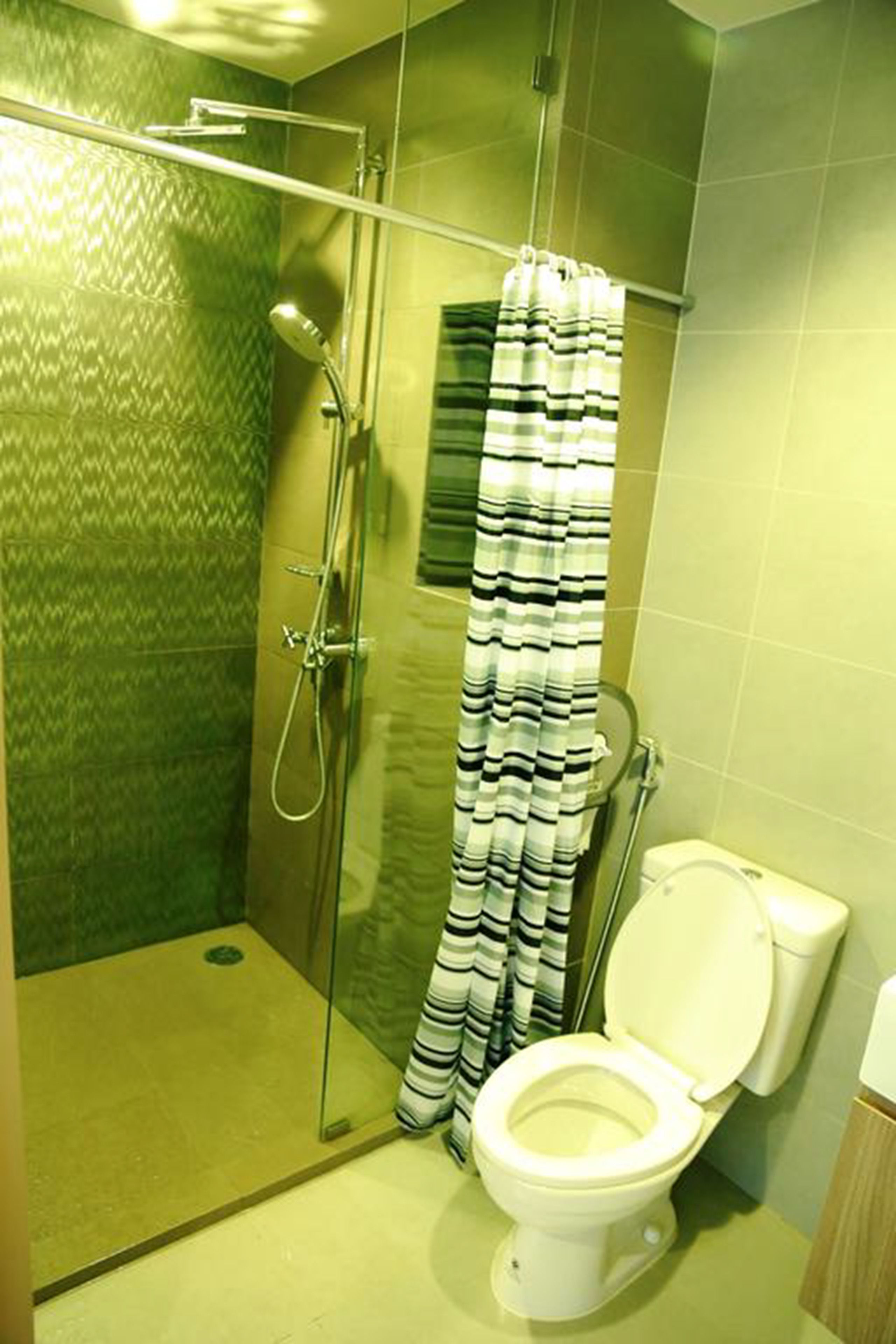 A shower with a glass door, a striped shower curtain, and a toilet with a closed lid.