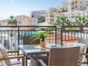 A balcony with wicker furniture, a glass table, and a potted plant. - Paradise Kings Club (Paphos)