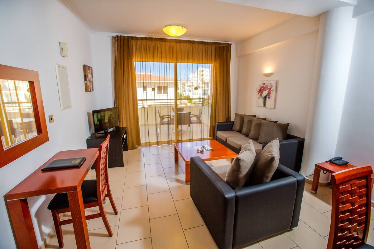 Una sala de estar con sofá, mesa de centro, televisor y un comedor con sillas y mesa.
