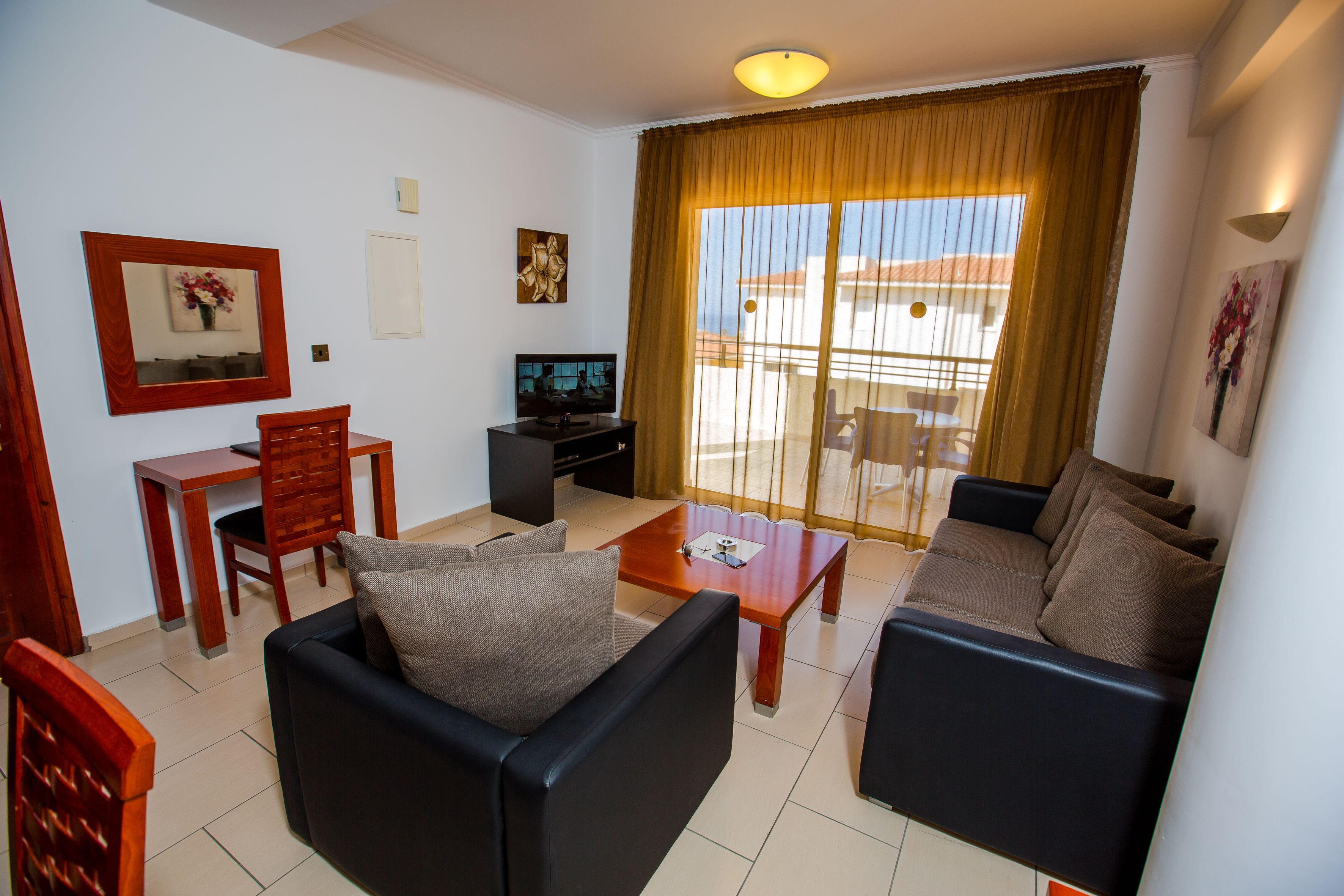 Una sala de estar con sofá, mesa de centro, televisor y comedor con mesa y sillas.