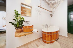 A bathroom with a wooden bathtub, a wooden shelf with a potted plant, a white sink, and a wooden window. - Vltavská pohádka (Cesky Krumlov)