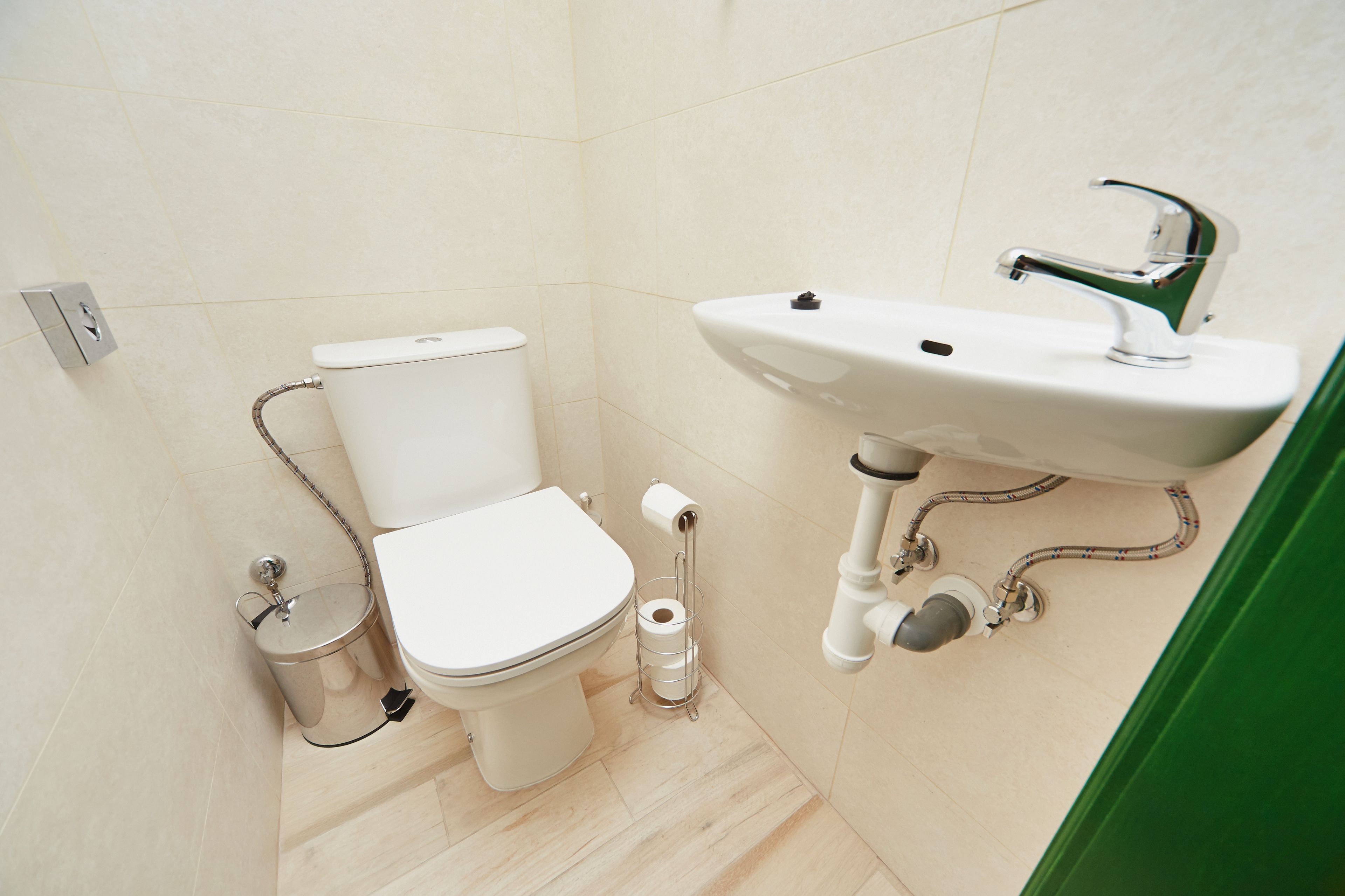 Un baño con inodoro, lavamanos y porta papel higiénico.