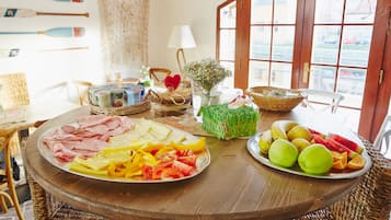A dining table with various food items, wicker chairs, and a view through a window.