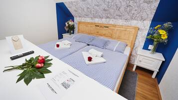 A neatly made bed with blue and white striped bedding, a wooden headboard, and a bedside table with a vase of flowers.