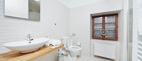 Un baño moderno con tocador de madera, lavamanos blanco y retrete.