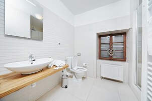Un baño moderno con tocador de madera, lavamanos blanco y retrete.
