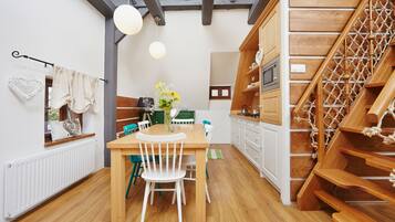 Una cocina moderna con armarios de madera, una mesa de comedor con sillas y una escalera de madera.