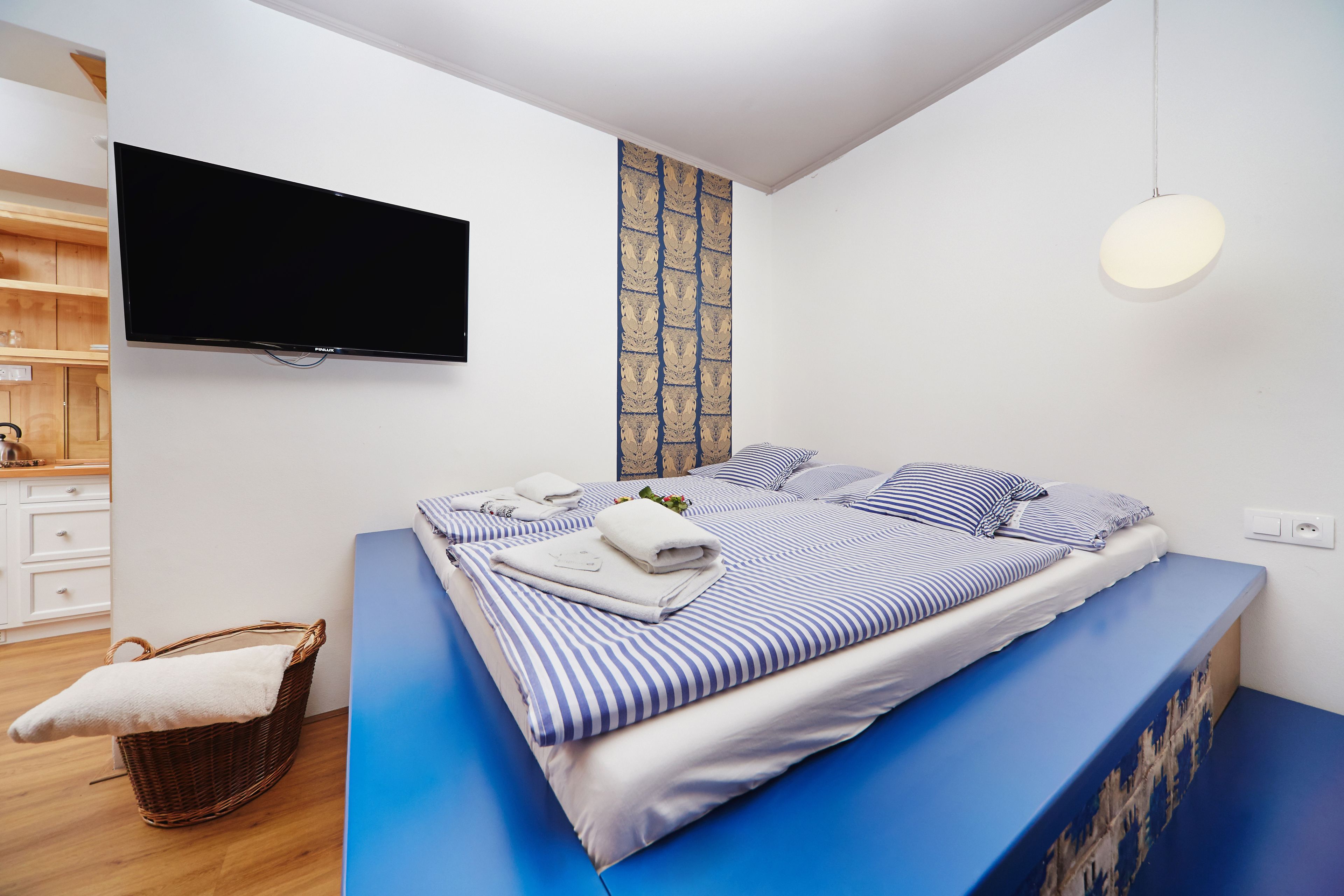Een moderne slaapkamer met een groot bed, een flatscreen televisie en een behang met een patroon.