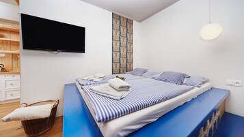 A modern bedroom with a large bed, a flat-screen TV, and a patterned wall.
