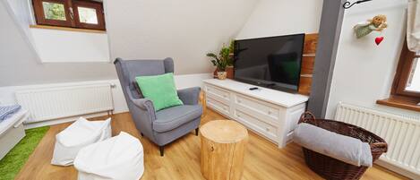 A modern living room with a grey sofa, a wooden coffee table, a television, and a wicker basket.
