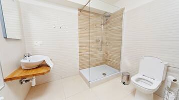A modern bathroom with a wooden vanity, a glass shower enclosure, and a toilet.