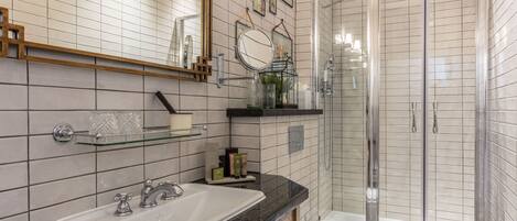 A modern bathroom with a white sink, a mirror, a glass shower enclosure, and a toilet.