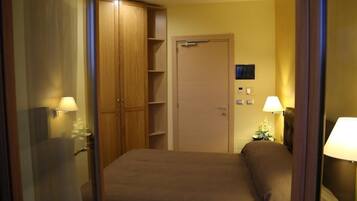 Une chambre d’hôtel avec un lit, une armoire, une porte et un téléviseur fixé au mur.