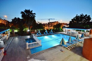 Una piscina al aire libre, sombrillas, sillones reclinables de piscina