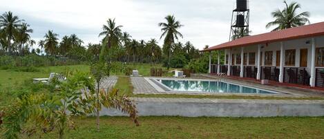 A pool area with a water tower, palm trees, and a building with columns.
