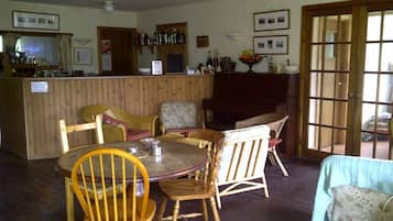 A cozy room with a wooden bar, several chairs, a table, and a fireplace.